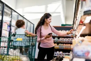 Mom shopping in grocery isle with little child in cart.