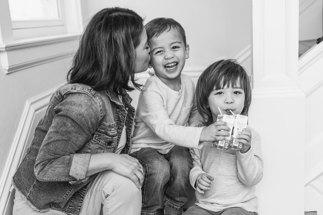 Mother sitting on stairs with two sons giving them rewards for good behavior.