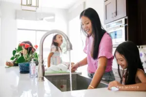 Mom doing dishes with two daughters in the kitchen with her